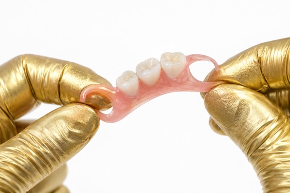 Flexible partial denture bending in gloved hands to show the nylon base gives
